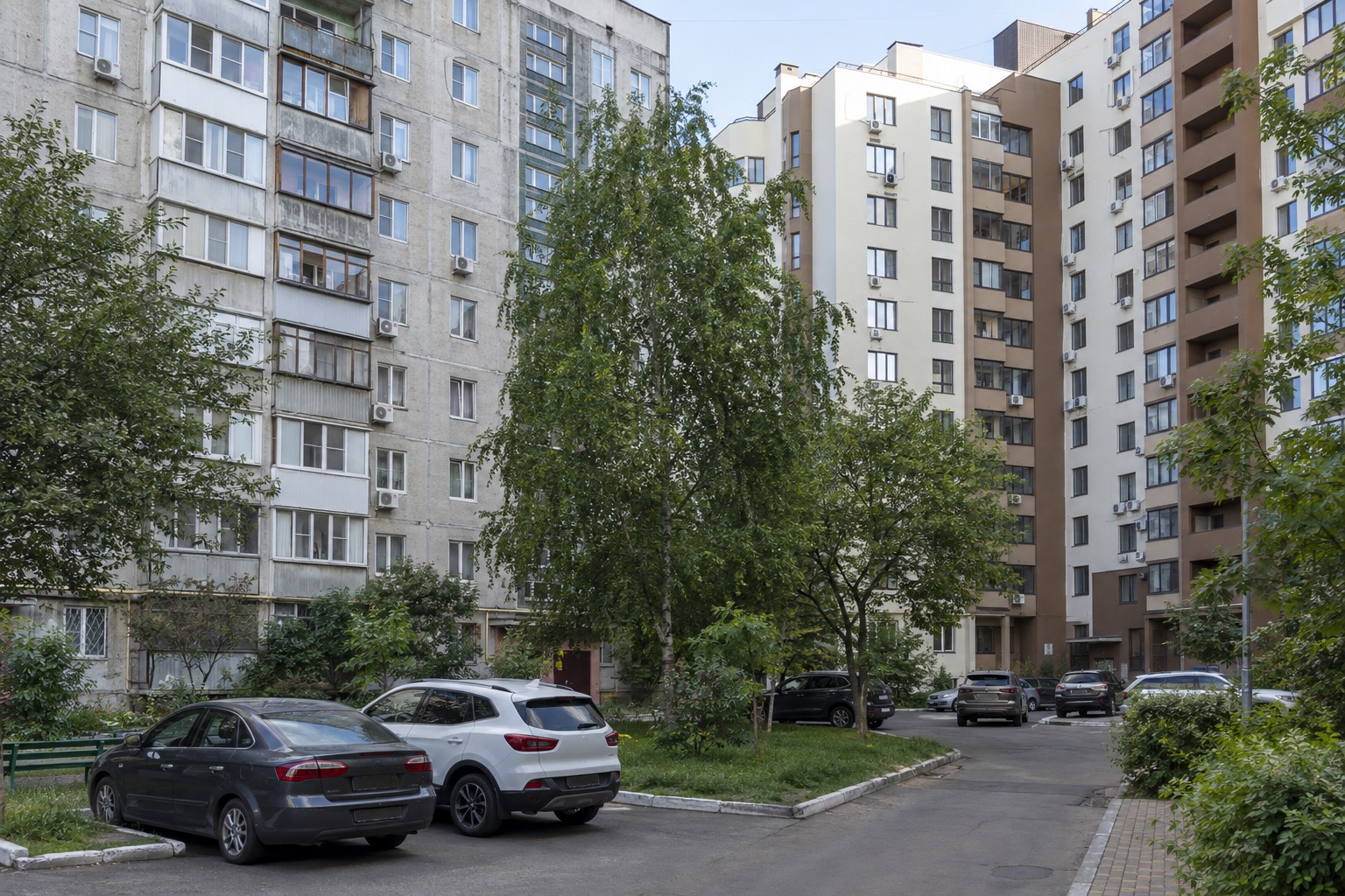 Панельна девʼятиповерхівка і новобудова поруч у дворі, типові для Вишневого