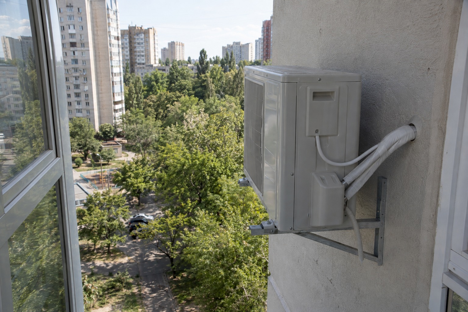Зовнішній блок кондиціонера на кронштейнах біля балкона, траса заведена в стіну
